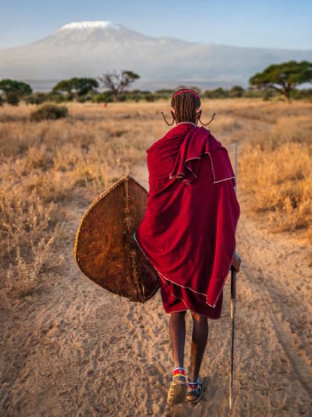 African warrior from Maasai tribe, Mount Kilimanjaro on the background, central Kenya, Africa. Maasai tribe inhabiting southern Kenya and northern Tanzania, and they are related to the Samburu.